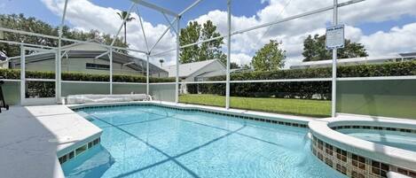 A swimming pool with a covered area, a hot tub, and a sign indicating pool rules.