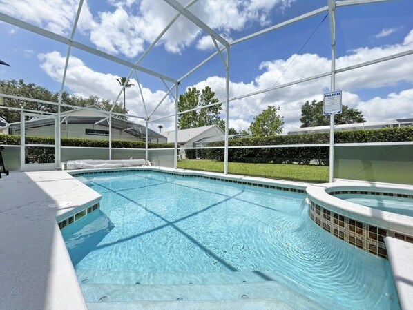 Una piscina con zona techada, un jacuzzi y un cartel que indica las normas de la piscina.