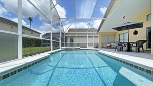 A swimming pool with a glass ceiling, surrounded by lounge chairs and a sunshade.