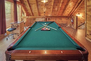 A pool table with a green felt surface, wooden surroundings, and a pool cue in the center. - Pool Table | Pigeon Forge | Hot tub | Fireplace | Arcade | WiFi (Pigeon Forge)
