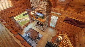 A log cabin interior with a stone fireplace, wooden ceiling beams, and a 'WELCOME' sign. - Pool Table | Pigeon Forge | Hot tub | Fireplace | Arcade | WiFi (Pigeon Forge)