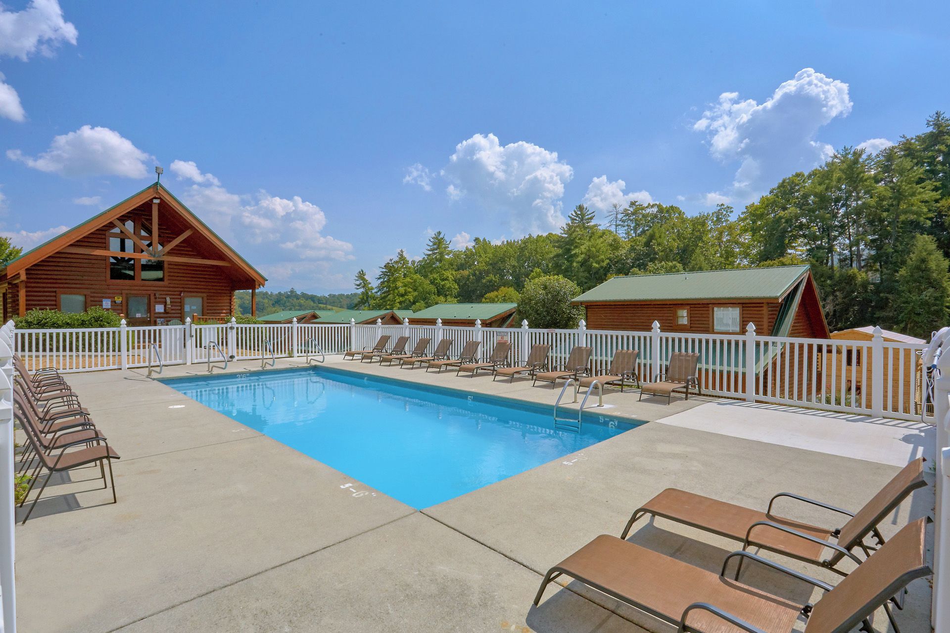 A pool area with lounge chairs and a wooden cabin structure.