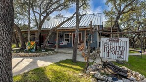 A rustic building with a porch, surrounded by trees and a stone wall. - Roz's Rusted Porch - Whitewater Amp, River, Lake (Canyon Lake)