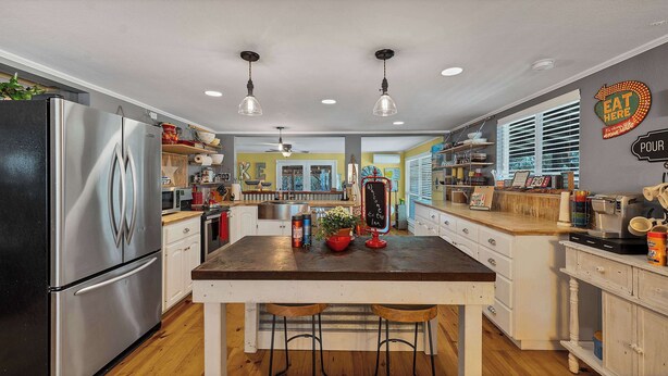 A modern kitchen with stainless steel appliances, a central island with stools, and a welcoming sign. - Roz's Rusted Porch - Whitewater Amp, River, Lake (Canyon Lake)