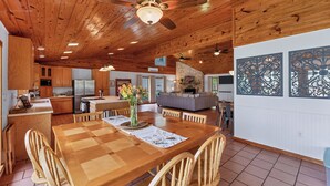 A spacious kitchen with wooden cabinets, a dining area with a wooden table and chairs, and a living area with a sofa and fireplace.