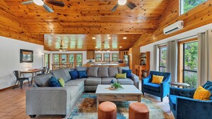 A spacious living area with a wooden ceiling, a gray sectional sofa, a blue armchair, and a coffee table.