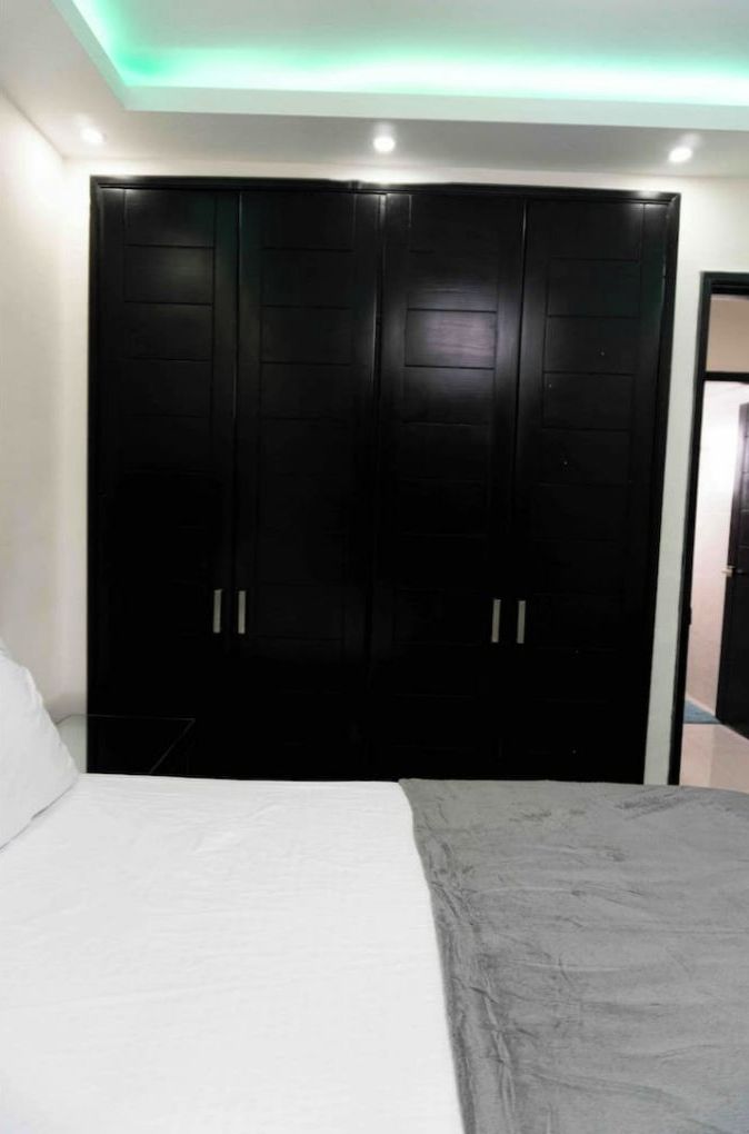 A bedroom with a bed, a large wardrobe, and a door leading to another room.