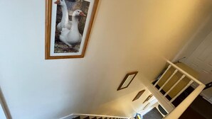A staircase with a framed picture of two white geese on the wall. - Impeccable 4-bed Home Away From Home in Swindon (Swindon)