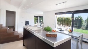 Una cocina moderna con una isla grande, muebles oscuros y vistas al exterior.
