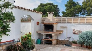 A backyard with a stone pool, an outdoor oven, and a white wall with a tiled border. - Villa Resi by Interhome (Miami Platja)
