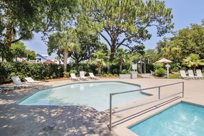A swimming pool with lounge chairs and a gazebo in a landscaped area.