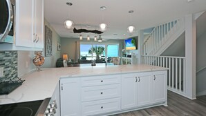 A spacious kitchen with a large island, white cabinetry, and a view to the outdoors.