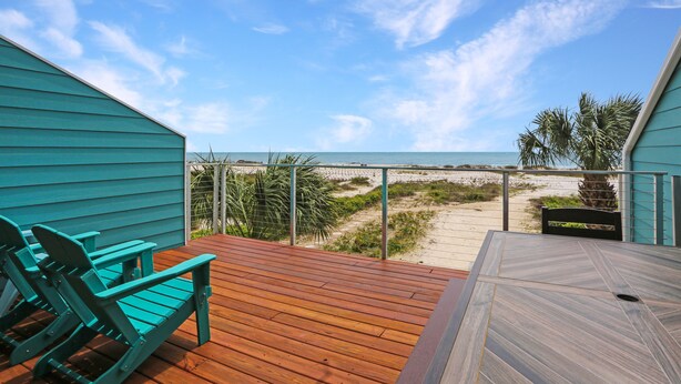 A wooden deck with a view of the beach and ocean.