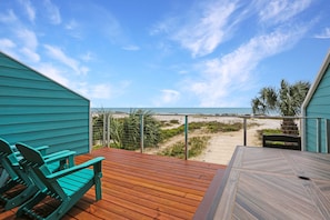 A wooden deck with a view of the beach and ocean.
