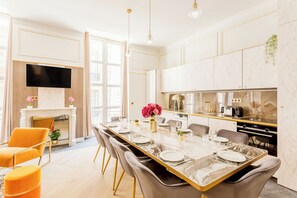 A modern kitchen with a large island, built-in appliances, and a flat-screen TV.