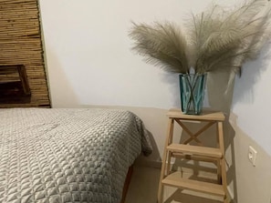 A bedroom with a bed, a wooden nightstand, and a vase with dried pampas grass. - Enjoy Chania - Hidden Gem in Citys Heart (Chania)