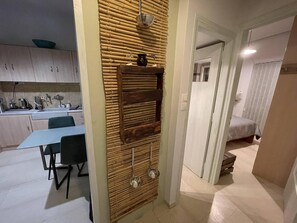 A modern kitchen with wooden cabinets, a dining table with chairs, and a bamboo wall panel. - Enjoy Chania - Hidden Gem in Citys Heart (Chania)
