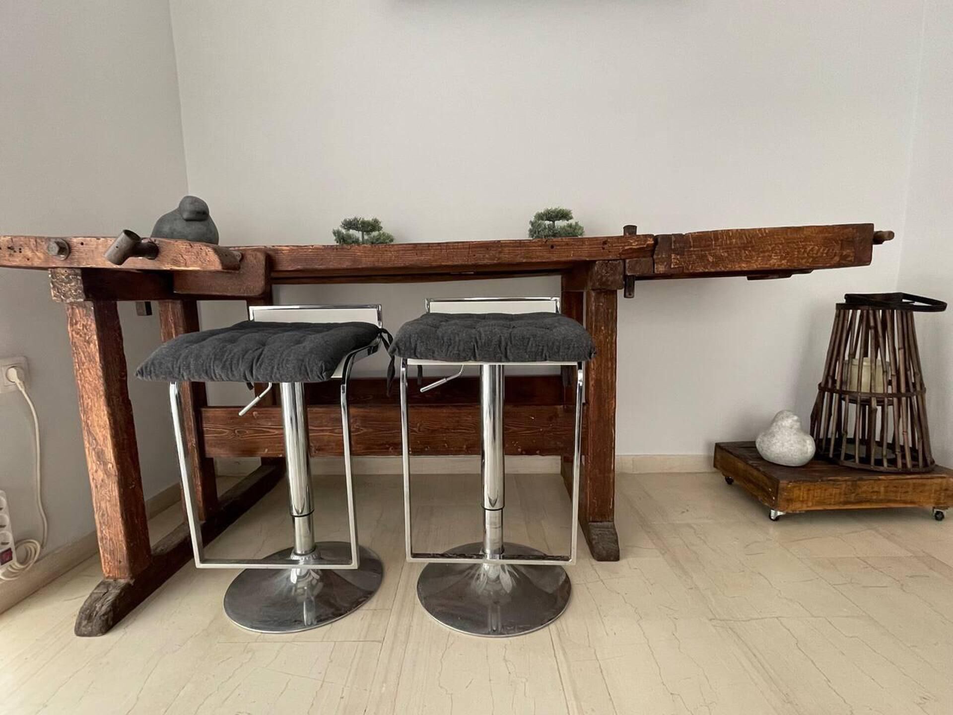 Un tavolo di legno rustico con due sgabelli in metallo, ognuno dotato di seduta imbottita.