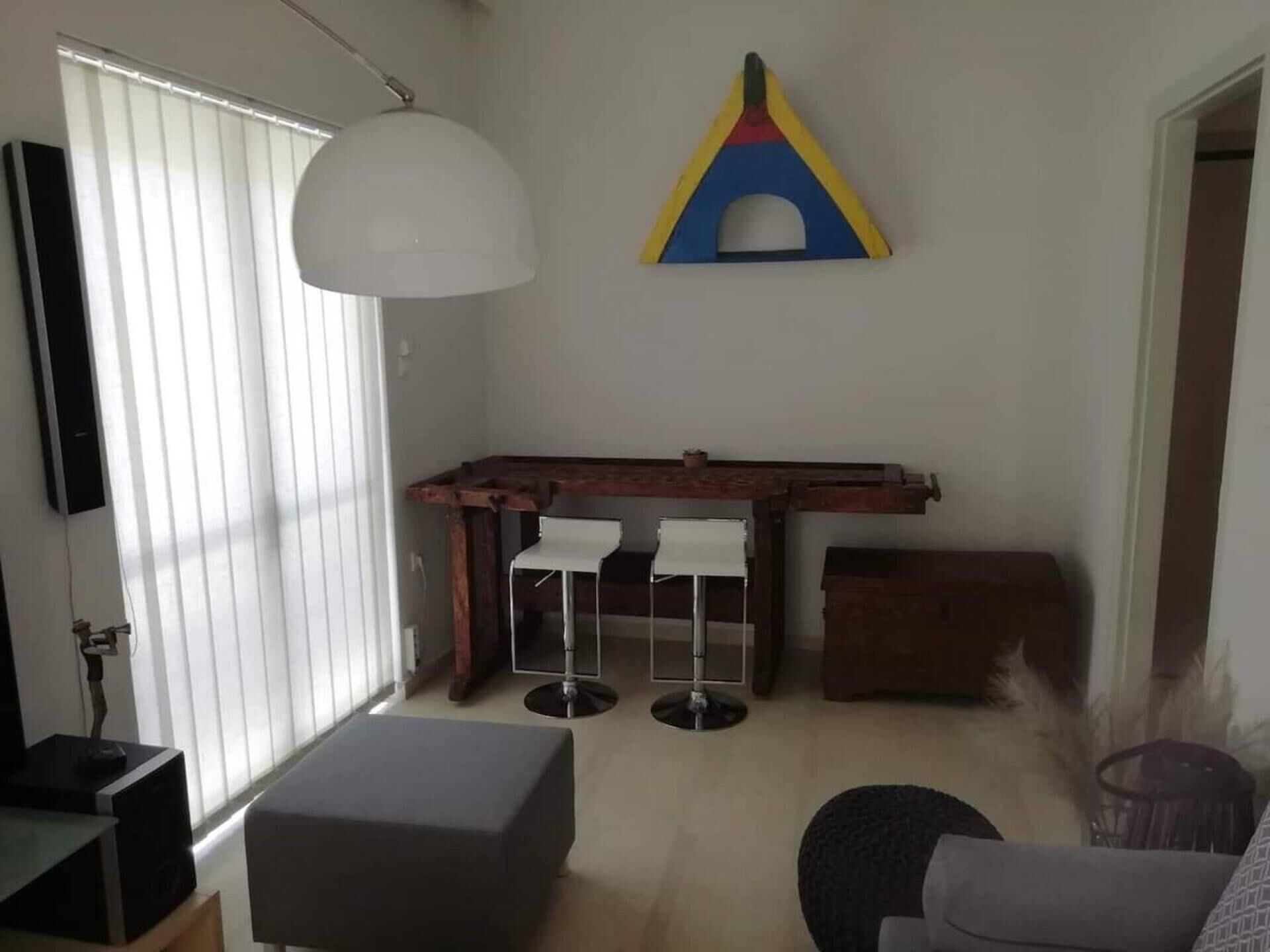 A compact living space with a dining area, a white pendant light, and a colorful wall decoration.