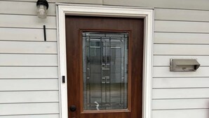 Eine Holztür mit Fensterglas, ein Briefkasten und eine Fußmatte.
