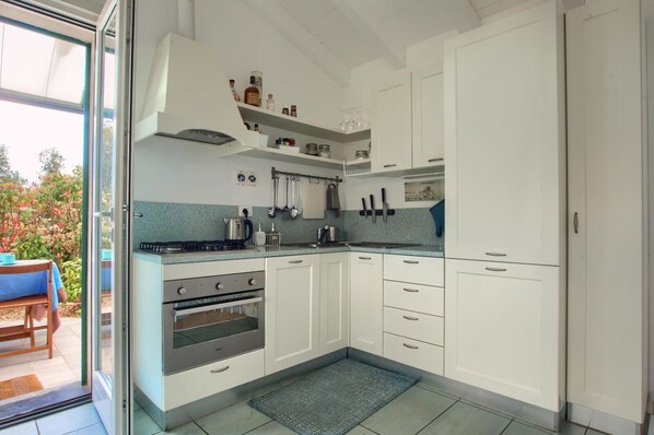 A modern kitchen with white cabinets, a gas stove, an oven, and a blue countertop.