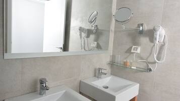 Une salle de bain moderne avec deux lavabos, un grand miroir, un sèche-cheveux et une poubelle.