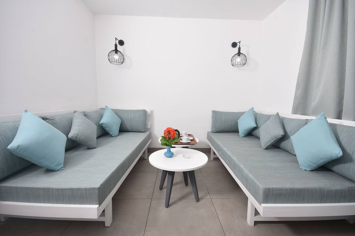A modern living room with two grey sofas, a white coffee table, and a vase with flowers.