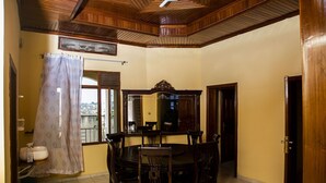 A dining area with a wooden ceiling, a round table, and six chairs. - Comfort Apartment  (Kigali)