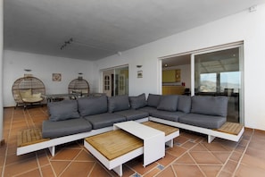 A modern living room with a sectional sofa, two coffee tables, and a dining area with a table and chairs.