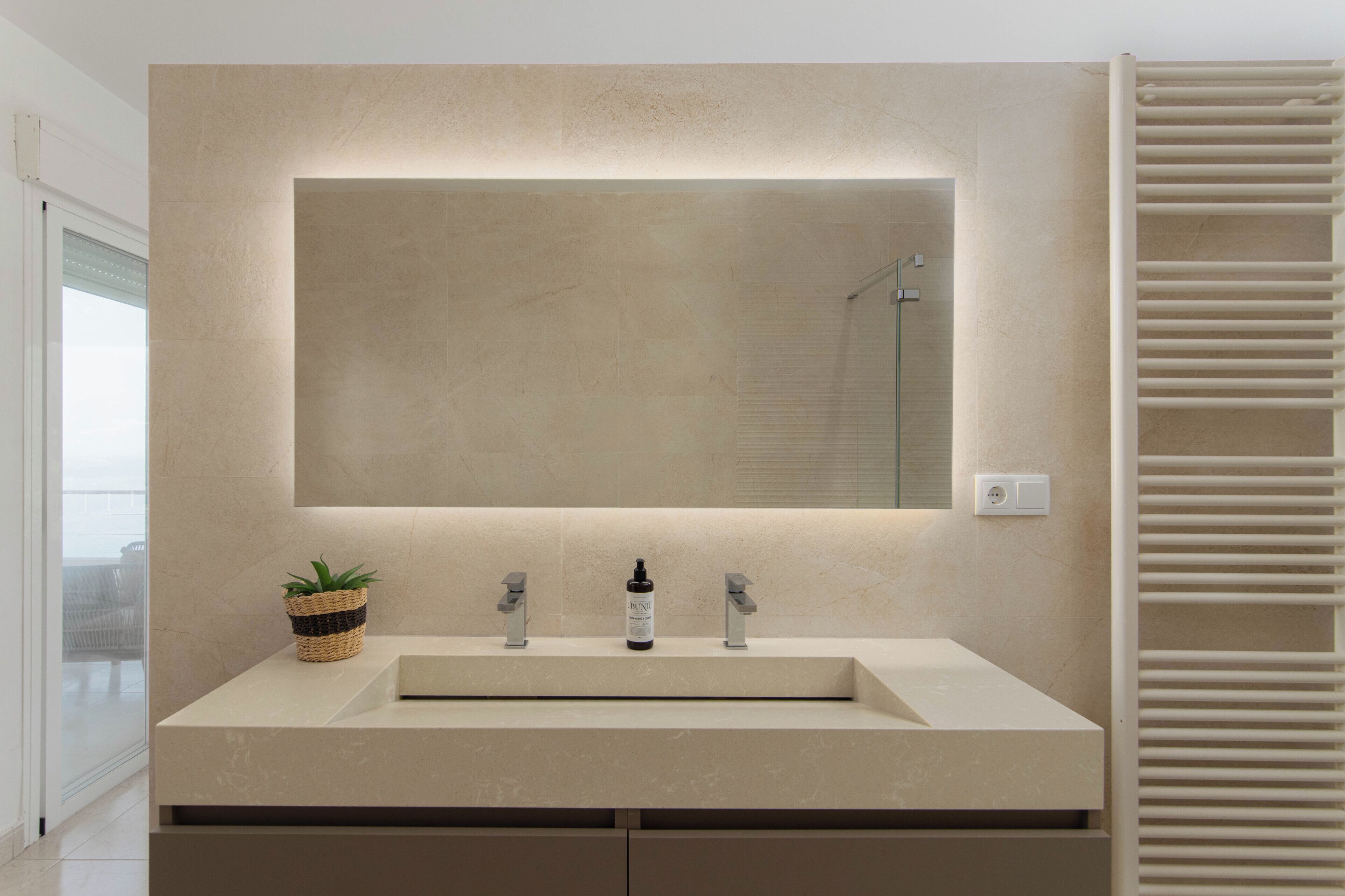 A modern bathroom with a large mirror, a sink, and a towel rack.