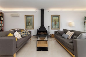 A living room with two sofas, a glass-top coffee table, a black fireplace, and framed artwork on the walls.