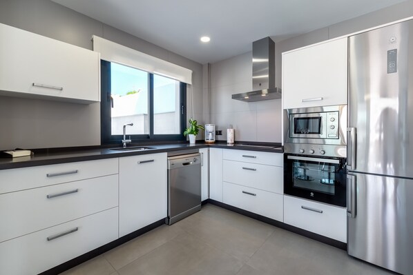 Een koelkast, een vaatwasser, kookgerei, borden en bestek