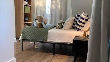 Ein Schlafzimmer mit Stockbett, Holzboden, Nachttisch, Sessel und Bücherregal.