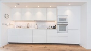 Una cocina moderna con armarios blancos, un horno doble y un backsplash con vista a la ciudad.