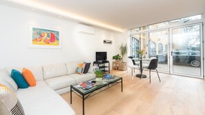 Una sala de estar moderna con un sofá, una mesa de centro, televisor y un comedor con sillas y una mesa.