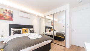 Una habitación de hotel moderna con una cama grande, un espejo y un cuadro en la pared.