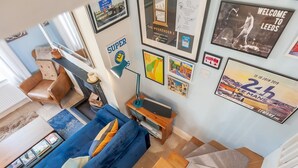Una sala de estar moderna con un sofá azul, una mesa de centro de madera y una escalera que sube a otro nivel.