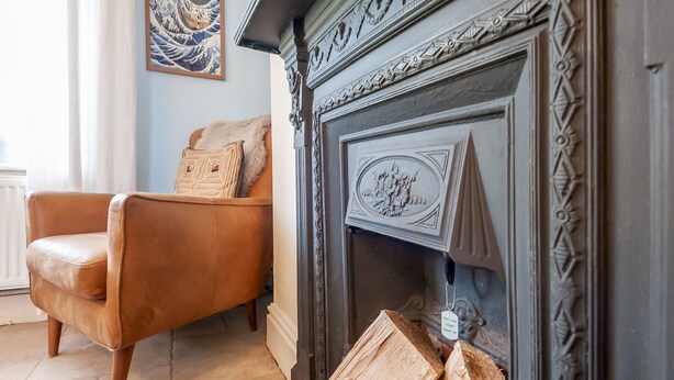 Una sala de estar con un sillón de cuero, una chimenea con detalles decorativos y una obra de arte enmarcada en la pared.