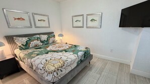A bedroom with a bed, nightstands, a lamp, and framed fish pictures on the wall. - 3/3 Duplex for 6+Shared Heated Pool, Tiki Bar BBQ (Hollywood)