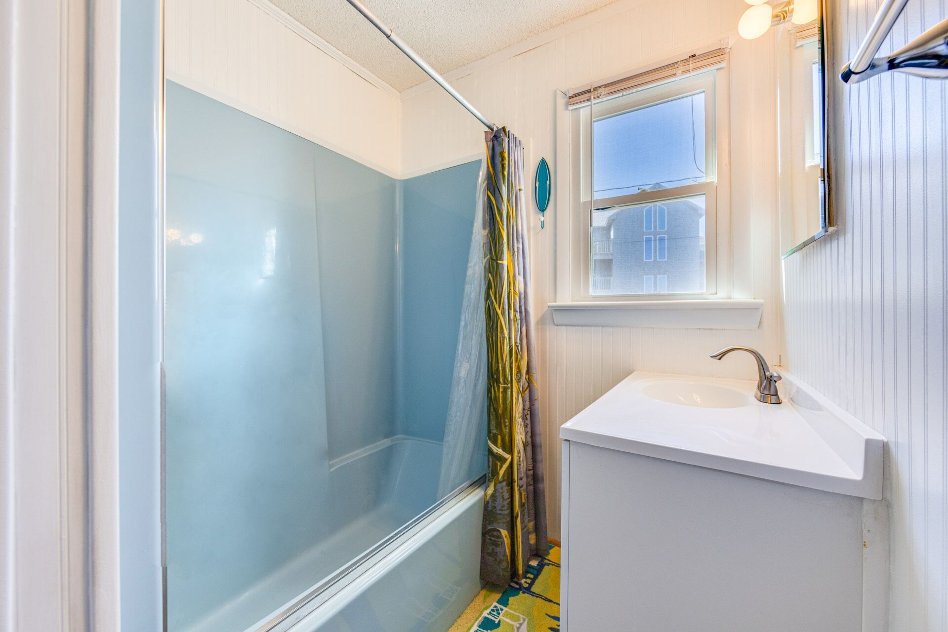 Ein Badezimmer mit Duschkabine aus Glas, Waschbecken und Fenster.