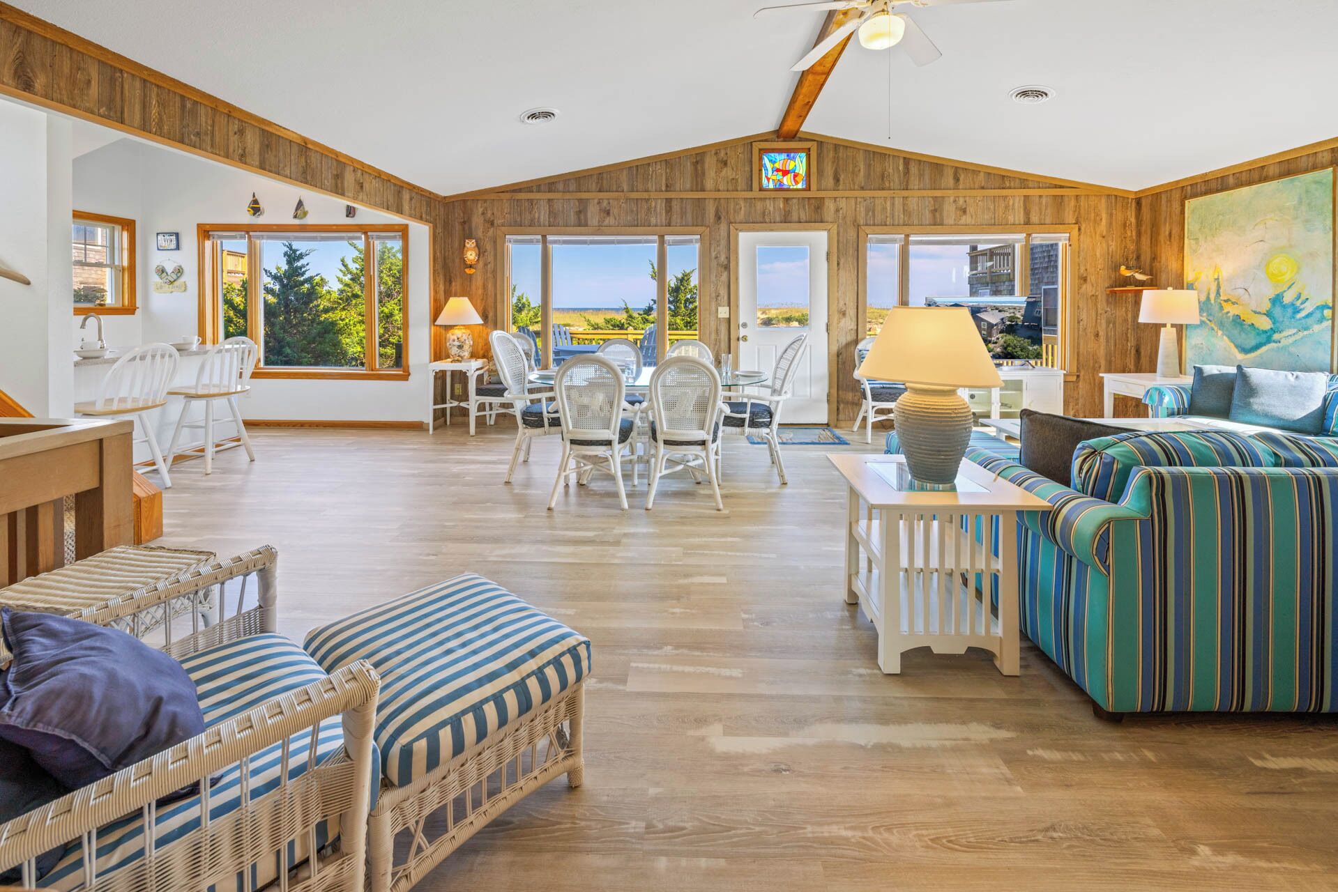 A spacious living area with a high ceiling, wooden walls, and large windows offering a view of the outdoors.