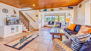 A spacious living area with a wooden ceiling, a staircase, and a view of the outdoors through large windows. - Oceanfront Home with Private Beach Access, Wet Bar, Grill, and Smart TV (Avon)