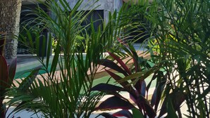 A modern building with a stone facade, balconies with plants, and a thatched-roof structure nearby. - Xentum Residences - Dreamed Condo (Tulum)