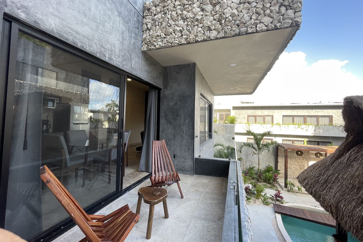Un espacio exterior moderno con piscina, muebles de madera y un muro de piedra.