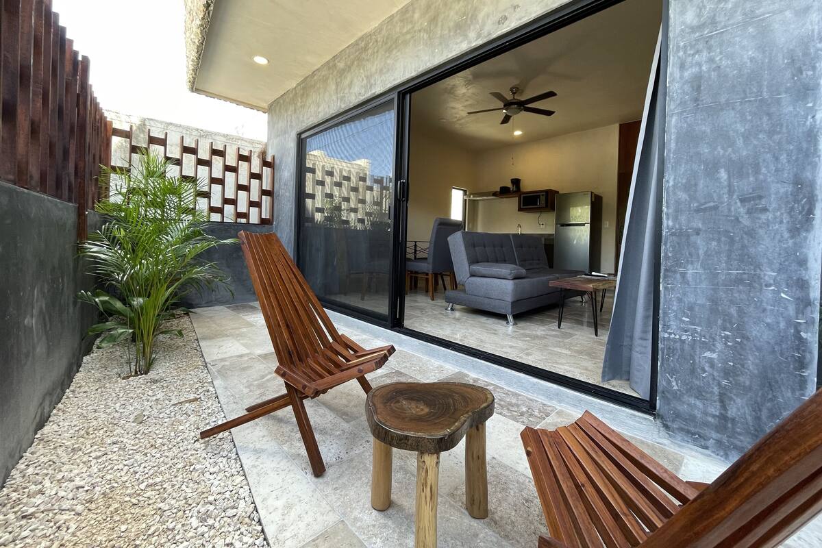 Un patio al aire libre con un banco de madera, una pequeña mesa redonda y una planta en maceta.