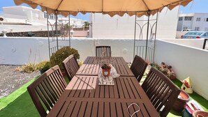 A rooftop terrace with a wooden table and chairs, a beige canopy, and potted plants. - Ganesh House 2 Bedrooms (Tías)