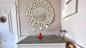 A room with a white dresser, a mirror with a circular frame, and a decorative wall piece. - Ganesh House 2 Bedrooms (Tías)