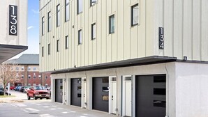 A modern building with numbered garage doors, a parking lot, and a clear sky.