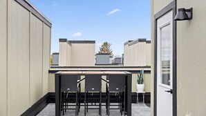 A balcony with a table and chairs, a potted plant, and a door.