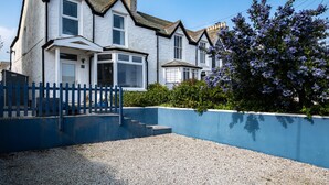 A two-story house with a blue front wall, a gravel driveway, and a blue fence. - Seapinks (Port Isaac)